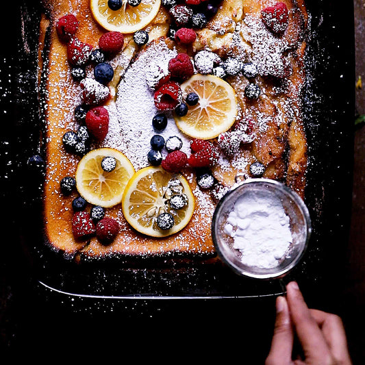 Fresh fruit cake with powdered sugar in an Xtrema ceramic baking dish