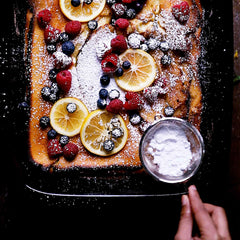 Fresh berries and lemon slices atop a powdered dessert in an Xtrema ceramic baking pan.