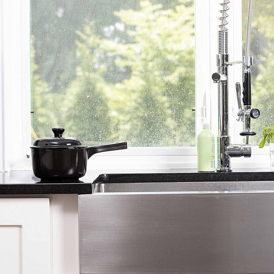 Black Xtrema ceramic pot on a kitchen counter next to a stainless steel sink.