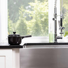 Black Xtrema ceramic pot on a kitchen counter next to a stainless steel sink.