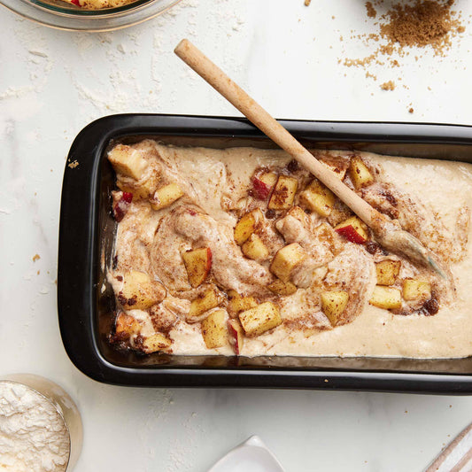 Apple cake batter with cinnamon and fruit chunks in a black Xtrema ceramic baking pan.