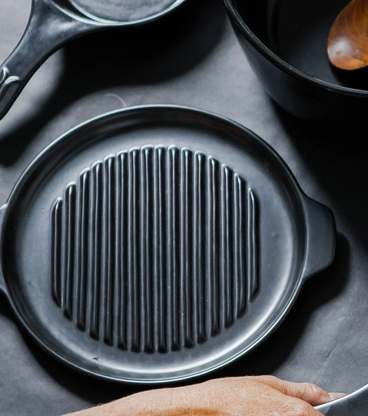 Xtrema black pure ceramic grill pan with ridged surface on a dark background