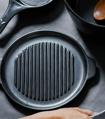 Xtrema black pure ceramic grill pan with ridged surface on a dark background