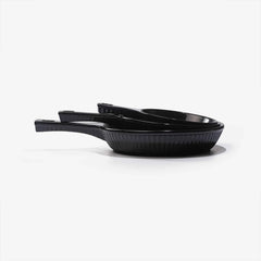 Three stacked black Xtrema pure ceramic cookware pans with handles on a white background.