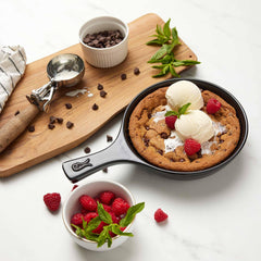 Chocolate chip cookie in an Xtrema ceramic skillet topped with vanilla ice cream and raspberries.