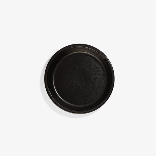 Top view of a matte black Xtrema pure ceramic pizza pan on a white background.