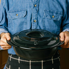 A person holding a black Xtrema pure ceramic covered casserole pot.