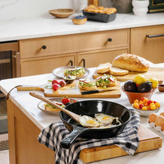 Xtrema ceramic skillet frying eggs on a kitchen counter with fresh breakfast appetizers.