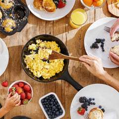 Scrambled eggs being served from an Xtrema ceramic skillet during a fresh breakfast spread.