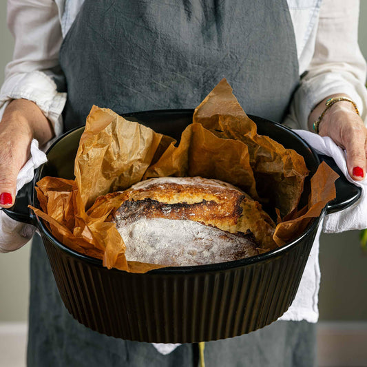 Freshly baked artisan sourdough bread in a black Xtrema ceramic baking dish.