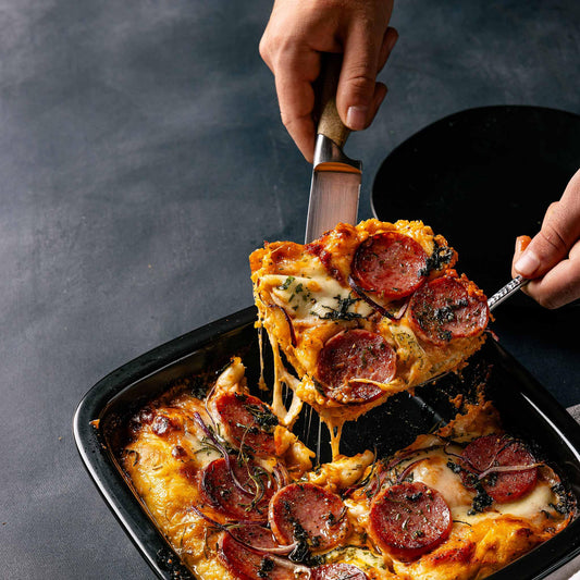 Serving a slice of pepperoni pizza from an Xtrema ceramic baking dish.