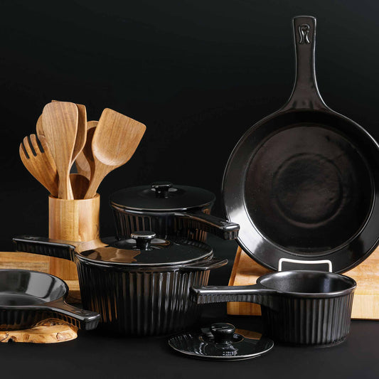 Xtrema black pure ceramic cookware set with matching wooden utensils on a black background.