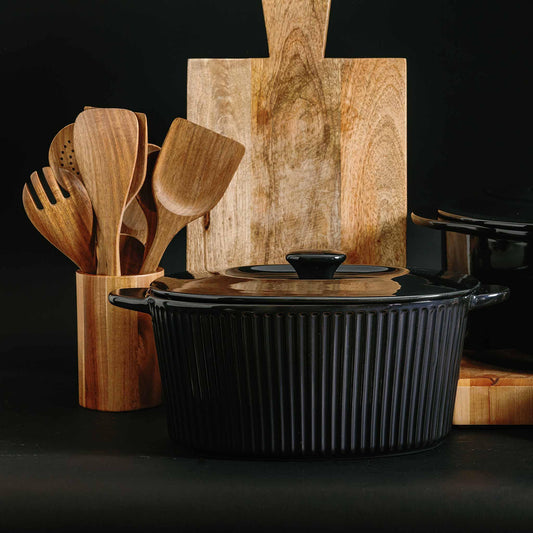 Xtrema black ceramic fluted casserole dish with lid, wooden utensils, and cutting board.