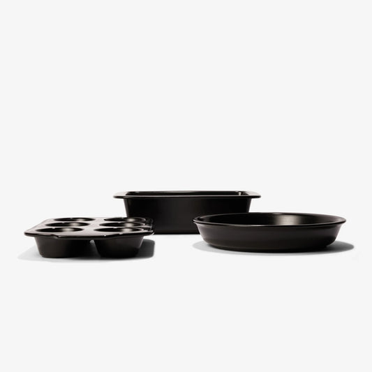 Set of black Xtrema ceramic bakeware including a muffin pan, rectangular cake pan, and round pan.