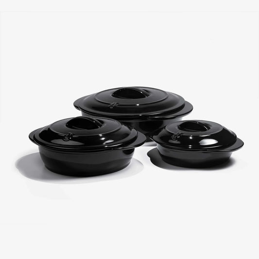 Set of three black Xtrema pure ceramic cookware pots with lids on a white background.