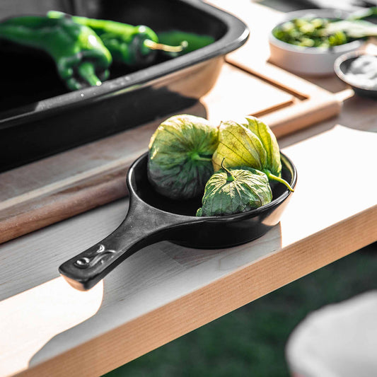 Physalis berries in a small black Xtrema ceramic pan on a wooden tabletop.