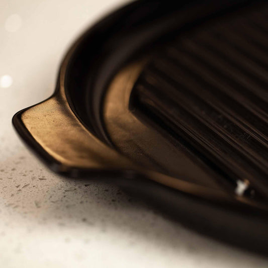 Close-up of a sleek, black Xtrema pure ceramic grill pan with a ribbed cooking surface.