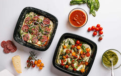 Two Xtrema ceramic baking dishes with gourmet appetizers, tomato sauce, and pesto.