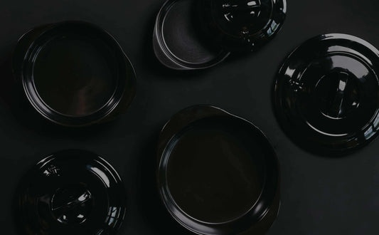 Top-down view of professional black Xtrema pure ceramic cookware on a dark background.