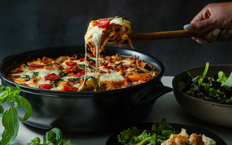 xtrema versa pan with cheese pull from a lasagna with tomatoes and fresh basil on top homepage hero image