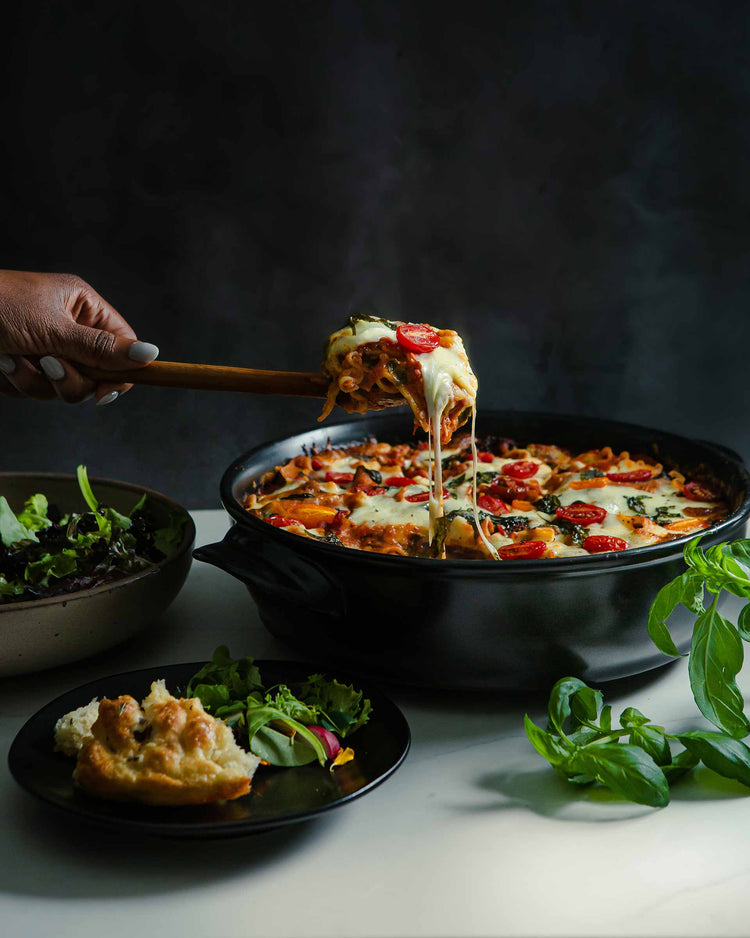 xtrema versa pan with cheese pull from a lasagna with tomatoes and fresh basil on top homepage mobile hero image
